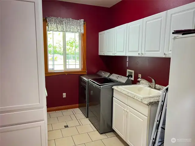 Utility room with storage cabinets and deep sink. Freezer conveys.