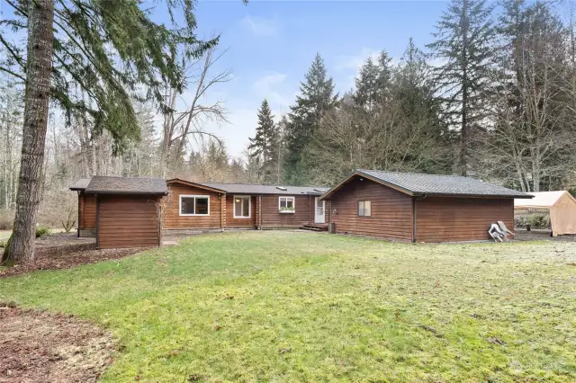 As viewed from the backyard area, you see the garage to the right, the storage/well building to the left, and the home itself to the center. What a well-thought-out layout this is! And it's been done for you, and is turn-key and move-in-ready now!