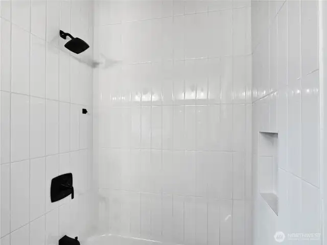 Tiled shower with recessed cubby in the main full bathroom