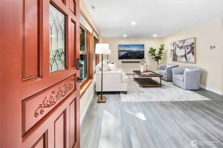 A carved wood entry door with decorative leaded-glass window sets a warm first impression, complemented by secure keyless entry. Step inside to light-filled living with new laminate wood floors and an inviting open layout.
