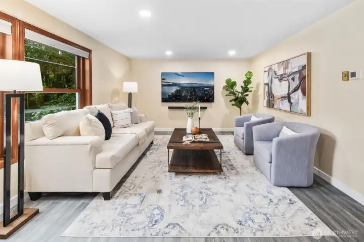 The living room is filled with soft recessed lighting that creates a bright, welcoming atmosphere. Beautiful warm-toned walls tie seamlessly into every room of the home, enhancing the open flow and sense of harmony throughout.