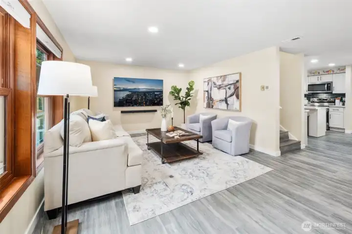 The living room opens seamlessly to the kitchen and dining areas, creating an easy flow for everyday living and entertaining. The warm wall color and continuous new laminate flooring tie the spaces together with a cohesive, inviting feel.