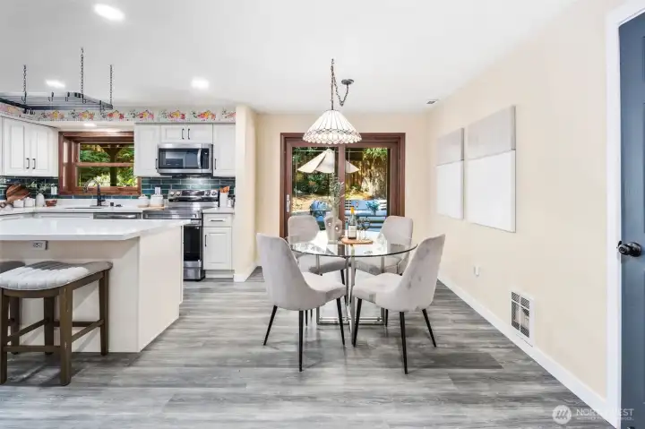 The dining area is anchored by a charming Tiffany-style chandelier that adds character and warmth. Matching wood-cased windows with new Levolor blinds carry throughout the home for a cohesive finish. A sliding glass door opens directly to the spacious back deck, blending indoor and outdoor living with ease.