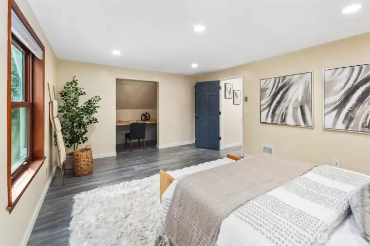 A large window overlooking the front yard fills the room with natural light, while a built-in desk alcove adds functionality—ideal for study, work, or creative projects. The rich slate blue doors echo the stylish updates carried throughout the main floor, creating a cohesive look across the home.