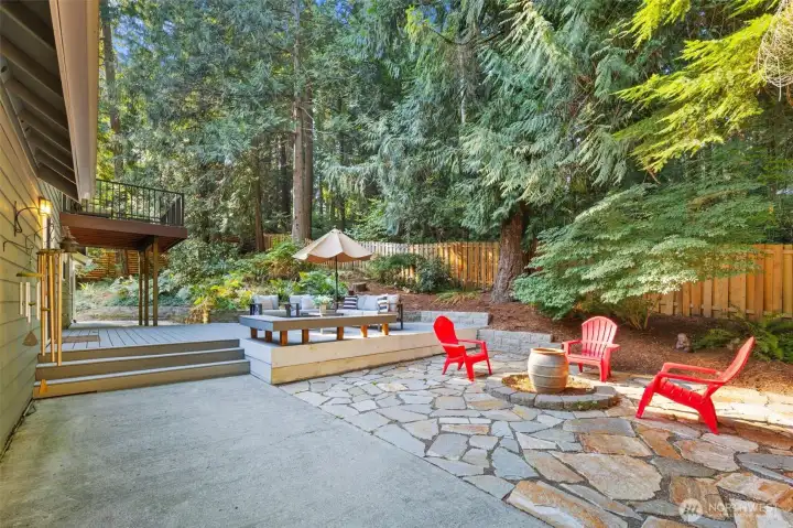 The backyard is designed for both entertaining and peaceful serenity, featuring extensive decking and multiple decorative stone patios. With dedicated areas for lounging and gathering around the fire pit, it’s a perfect setting for summer evenings and year-round outdoor enjoyment.