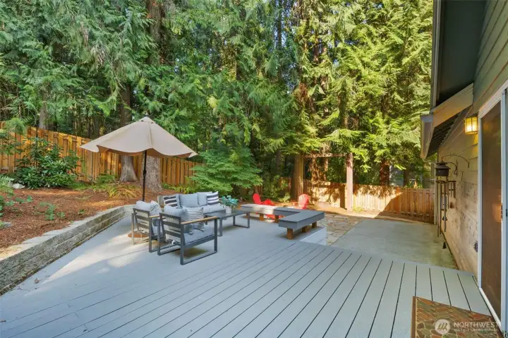 New fencing, added in fall 2024, preserves a natural wood look that blends seamlessly with the forest surroundings. Expansive composite decking, installed in 2023, offers a clean, modern surface that is both durable and low-maintenance. Imagine stepping out onto this private deck after a long day, breathing in the cool forest air, and feeling completely at peace.
