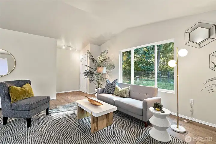 Large windows in the living room frame the tranquil backyard, filling the space with natural light and offering a calming connection to the outdoors.