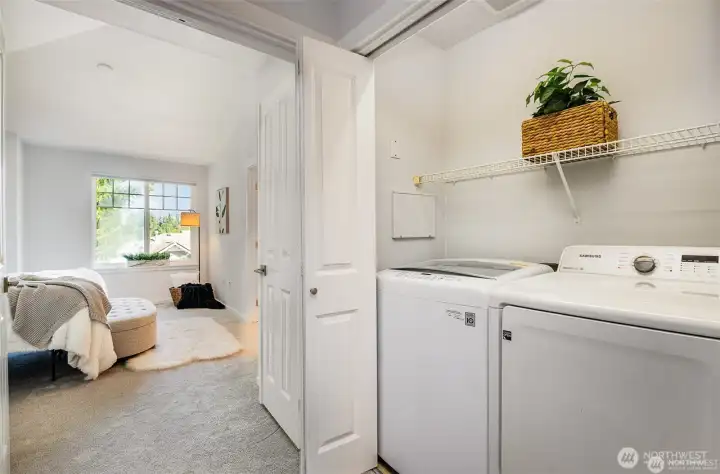 Laundry area with side by side washer and dryer in the hallway between guest bed and primary suite.