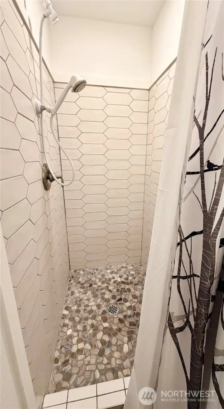 Primary bathroom boasts a tile shower w/stone floor