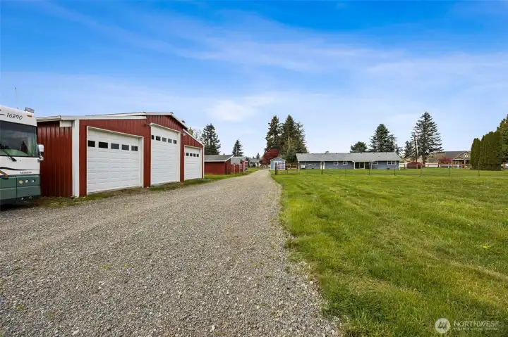 Looking from the 36’ x 36’ shop back toward the house, you get a sense of how well this property functions, with room for additional RV parking and easy maneuvering that does not feel cramped or improvised. And the shop itself is a powerhouse with new concrete floor, new roof, gutters, insulated doors with automatic openers, insulated ceiling, exterior lighting, plus a sub electric panel already in place. Add a 30-amp RV hookup and separate 110 plug for a motorhome, and this starts checking boxes fast. The first and third bays offer 9-foot doors, while the center bay rises to 13 feet for larger needs. Also, the remote openers work from the kitchen, so if rain starts coming down and the doors were left open, you can handle it without ever running outside.