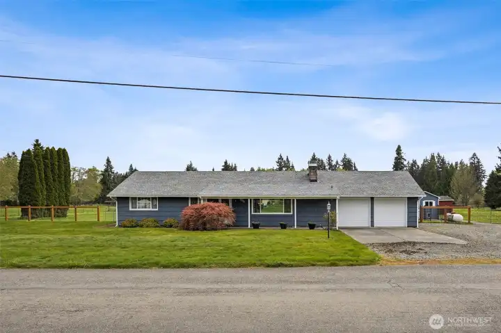 Classic mid-century rambler lines keep this home grounded, while the stormy blue cedar siding with crisp white trim gives it a fresh, collected look that feels current without losing character. And that Japanese maple by the front door is doing what a great specimen tree should do, adding a little artistry right where you arrive. The covered walkway from the driveway to the front door is one of those practical touches that becomes surprisingly appreciated in Northwest weather. And with the roof installed in 2021, there is substance behind all this charm.