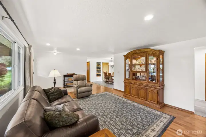This living room has a calm confidence about it. Beautiful oak hardwood floors bring texture and warmth, while recessed lighting gives the room a clean, updated feel. What really comes through here is the flow, living, dining, kitchen all working together in a way that feels natural and easy. You can picture gatherings spilling from one space into the next without anyone getting boxed into a corner. Even the coat closet gets points here, adding smart storage right where daily life happens.