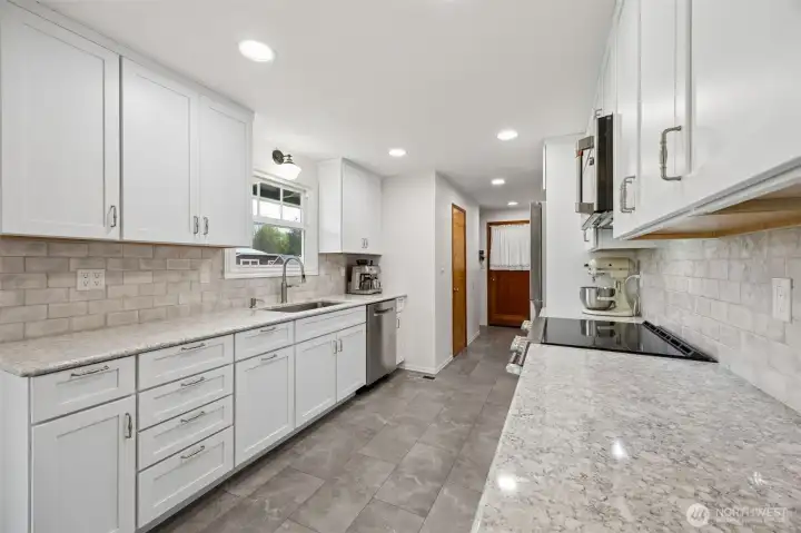 The bones were always good, now the $70,000 remodel lets them shine. Warm gray tones, crisp white shaker cabinetry, brushed nickel hardware and a full tile backsplash running from counter to cabinet keep the look fresh, clean and timeless. New stainless appliances step in strong, with a Café electric cooktop, Bosch dishwasher, deep single-basin sink and pull-down faucet all doing their part. Composite countertops bring beauty with durability, which matters on a property where life can be a little more hands on. And then there is that view over the sink, looking out to pasture.