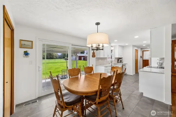 The dining area has generous room for a true farmhouse table and the kind of gatherings that tend to run long because no one wants to leave. Looking into the kitchen, you really see the impact of that $70,000 remodel, bright finishes, thoughtful design, and a space that feels lifted well beyond ordinary. Then the sliding glass door keeps drawing you outward, connecting everything to the backyard and making indoor-outdoor entertaining feel natural. Open the slider during a barbecue and the whole house expands.