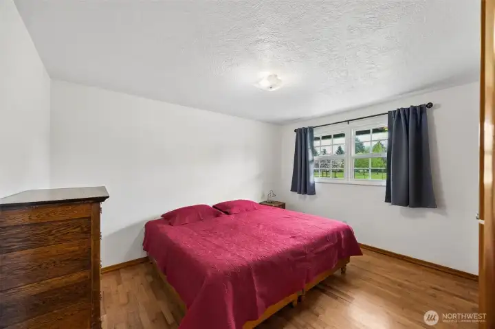 In bedroom #2, a generous back-facing window brings in beautiful natural light, the oak hardwood floors add warmth underfoot, and the fresh white paint throughout gives the room a clean neutral backdrop ready for whatever style the next owner brings. This is a king bed showing how large this room is. It feels bright, calm and easy to make your own. And comfort here goes beyond what you see. The home has a newer electric heat pump, only about three years old, plus central A/C tied into the ducted forced-air system, so heating and cooling move efficiently through the whole house.