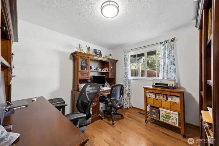 Used here as a home office, this second bedroom shows off its versatility in a big way. There is room for two distinct workspaces, which is no small thing, and it opens the door to all kinds of possibilities. Shared office, guest room with workspace, hobby room, you can take it in several directions thanks to the two closets in this room. The oak hardwood floors bring richness underfoot, and the front-facing window draws in soft natural light that makes the whole room feel energized. It is practical, comfortable, and has that quiet kind of flexibility buyers tend to notice.