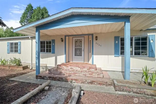 Charming covered front porch accented by raised flower beds on either side.