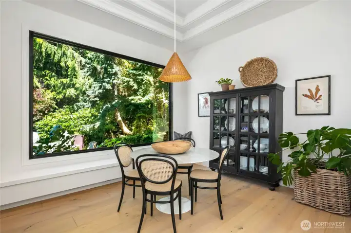 Stunning breakfast nook framed by a picture window with serene garden views and crafted trayed ceiling that adds depth and architectural interest.