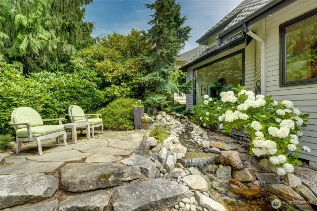 Tranquil garden retreat featuring a flagstone patio, and a serene cascading water feature—perfect for relaxing and enjoying your morning cup of coffee.