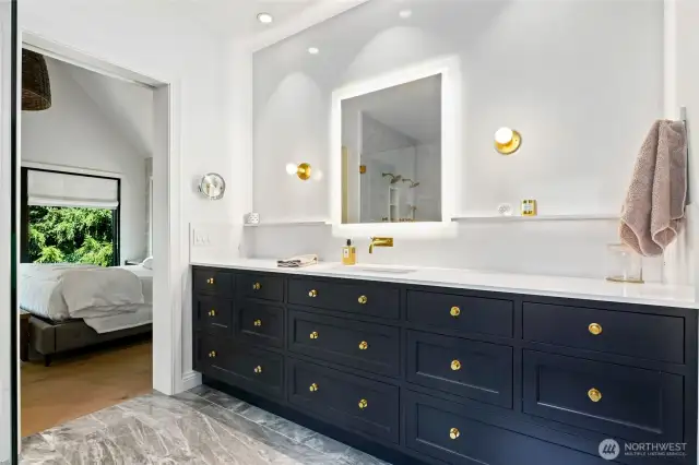 Luxurious primary bathroom with dual-sink vanity, gold fixtures, LED-lit mirror, and sleek custom cabinetry—designed with modern elegance and functionality in mind.