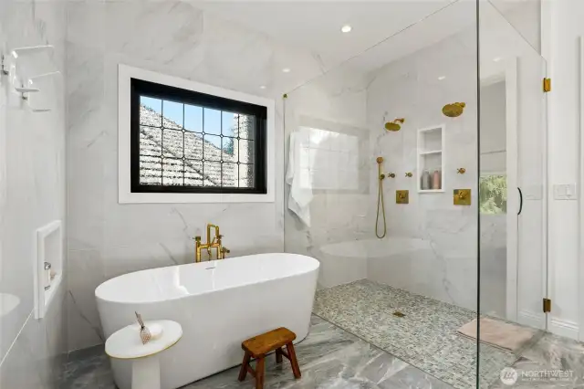 Spa-inspired primary bath featuring a freestanding soaking tub, walk-in glass shower with dual rain heads, designer tilework, and heated floors for a timeless, elevated retreat.