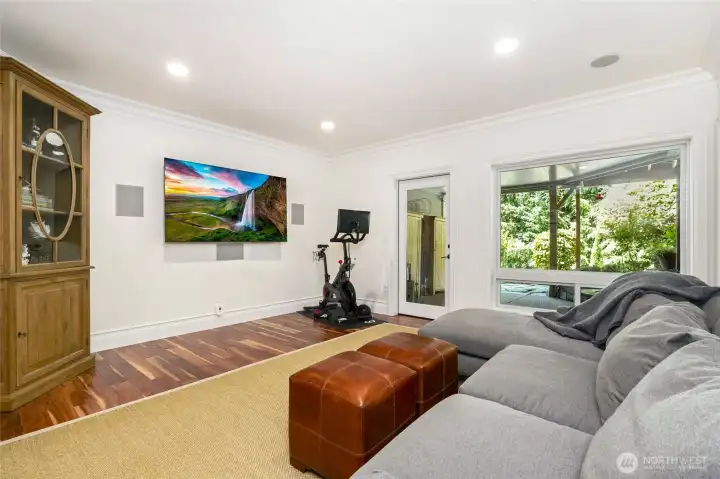 Versatile lower-level bonus room with large windows, custom millwork, built in surround sound and space for media, fitness, or relaxation—offering flexible living with direct outdoor access.