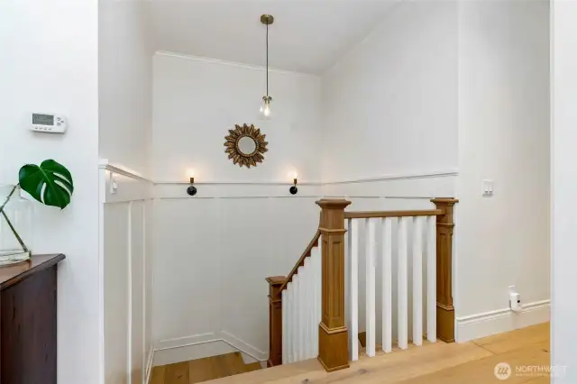 Elegant stair landing with custom millwork, wood and white spindle railing, and designer lighting—offering a bright and stylish transition between levels.