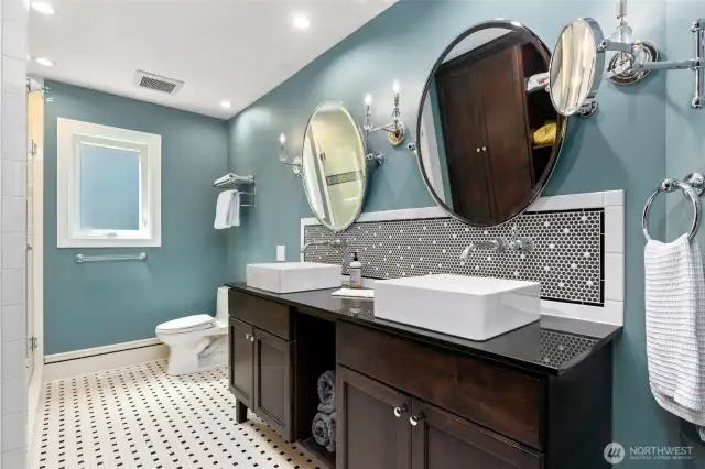Stylish full bathroom featuring dual vessel sinks, rich wood vanity, vintage-inspired penny tile backsplash, and classic black-and-white mosaic flooring.