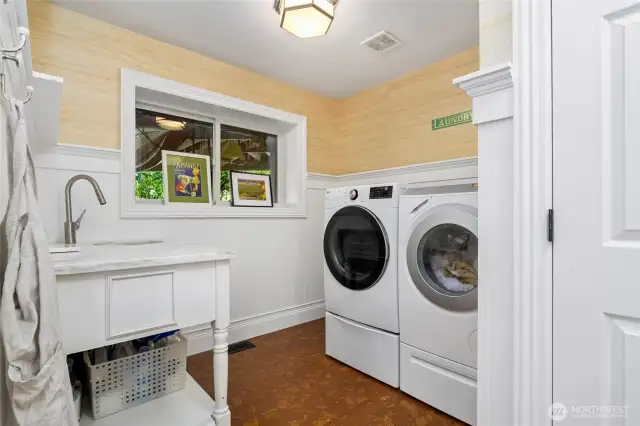 Bright and functional laundry room with a built in utility sink with marble countertop for folding laundry, and custom trim detailing. Also located in this room is the hose to the full home central vacuum.