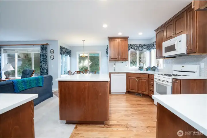 This perspective showcases the kitchen’s open flow, modern quartz surfaces, and classic beech wood cabinetry—perfect for cooking and gathering.