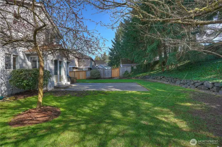 The level backyard and cement patio create a functional and inviting outdoor space for all your activities.