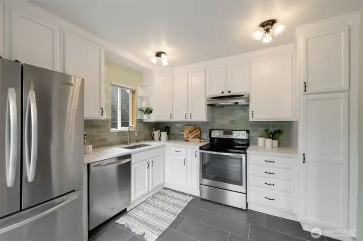 The kitchen features solid surface countertops, a newly tiled backsplash, and stainless steel appliances