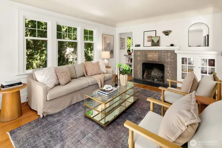 Bright living room with period details: original hardwoods, wood burning fireplace & coved ceilings