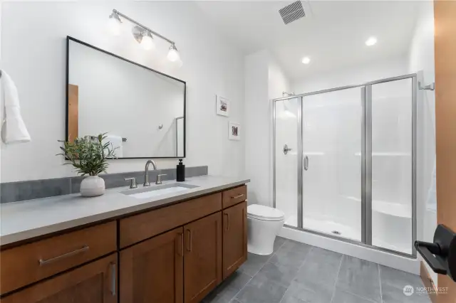 Upper level loft area bathroom with ceramic tile flooring and quartz countertops.