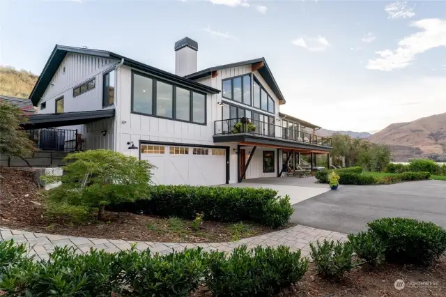 View of home w/ attached garage, wraparound view deck and surrounding landscape.