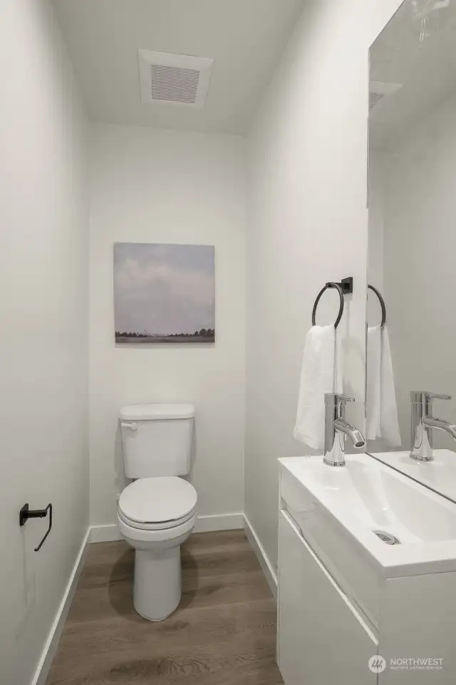 This discreet powder room features a minimalist design, offering guests a sleek and functional space.