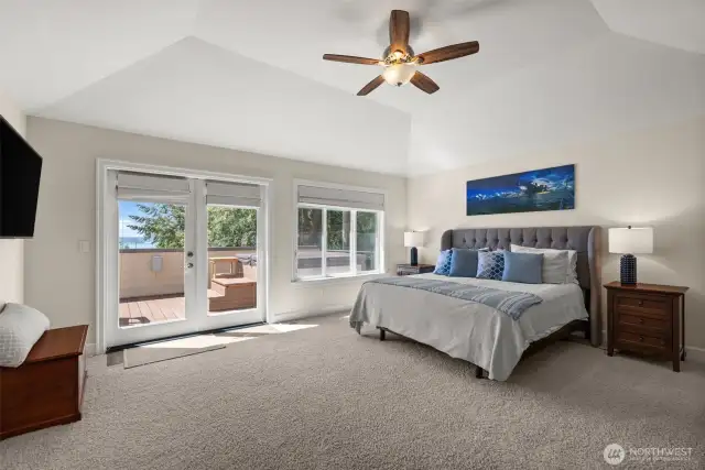 Primary bedroom with deck & hot tub, full bath, walk-in closet & view of the water