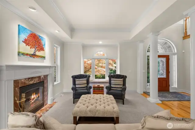 Living room with box beam ceilings, fireplace and bench seating by the window