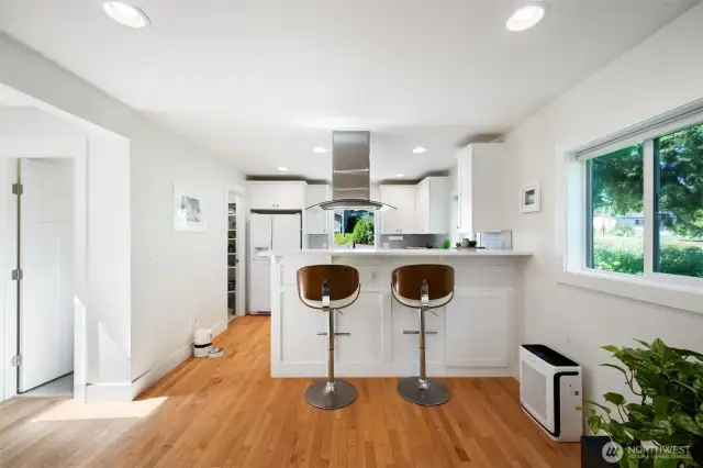The modern kitchen has a quartz bar. To the left is a half bathroom.