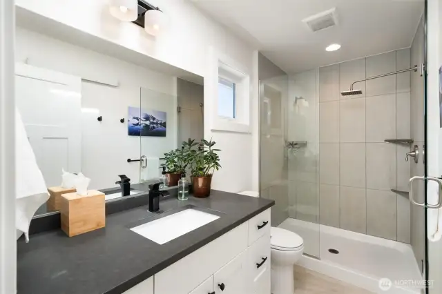 Upstairs bathroom with quartz counters and stylish walk-in tile shower with a rain shower head for spa-like comfort.