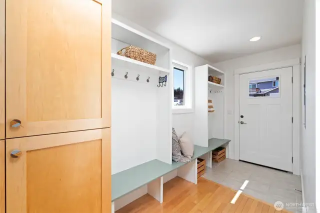 Step inside the welcoming entry to warm maple wood floors, a skylight and built-in bench seating, coat hooks, and storage cubbies.