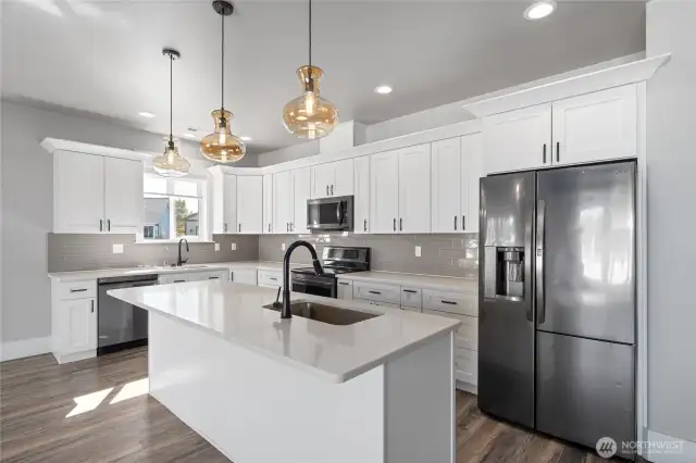A chef’s dream kitchen featuring custom cabinetry, gleaming quartz countertops, beautiful appliances, and designer lighting
