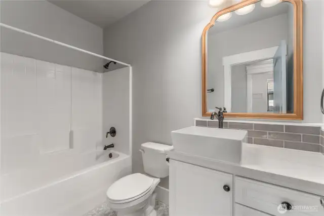 Impeccably finished, the guest bath combines tasteful tile flooring and backsplash with upscale designer touches for a polished look
