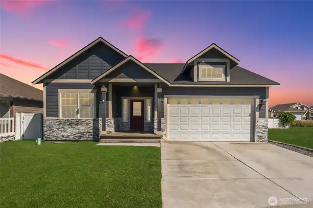 A welcoming and elegant covered front entry, beautifully framed with timeless stone accents for stunning curb appeal