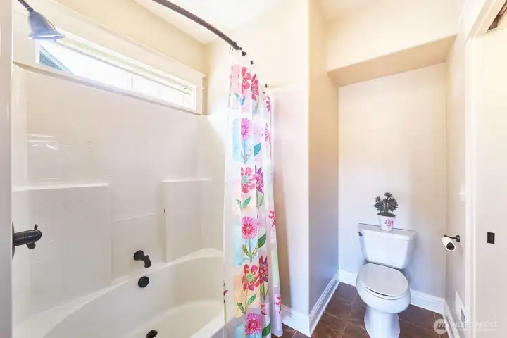 Full bathroom with rounded tub and a window for daylight entry.