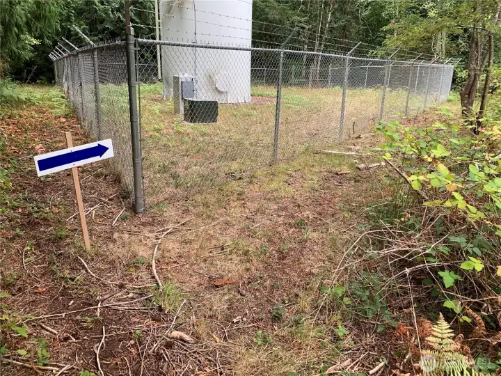 Your water comes from here. Easement road is on the far side of the fence. Walk down it until you get to neighbor's gate and then continue down the hill until you come to the stairs.