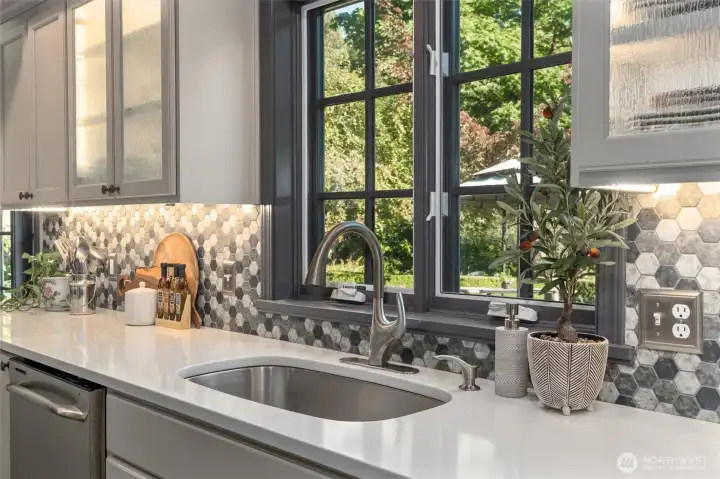 Large stainless sink overlooks the gardens, while windows swing open to let in fresh air.