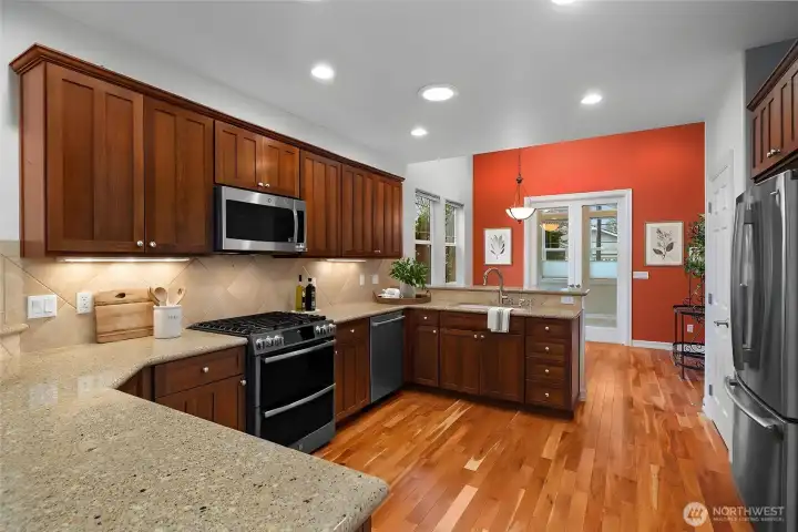 Beautifully updated kitchen featuring quartz countertops, hardwood floors, a new gas oven and range, dishwasher, and microwave. Upgraded cabinetry with pull-out shelves and a charming eat-in space make this kitchen both stylish and functional.