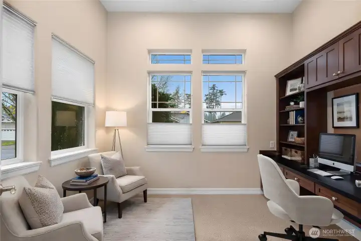 Bright and spacious den/flex space featuring custom built-in cabinets and a desk perfect for a home office, study, or creative workspace.