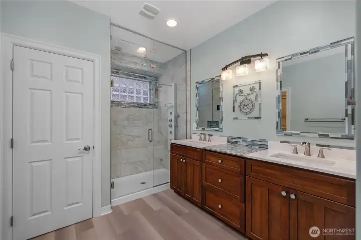 Remodeled primary bathroom featuring a luxurious full-tile steam shower, elegant marble countertops, a double vanity, and a custom-designed closet system—spa-like comfort meets thoughtful design.